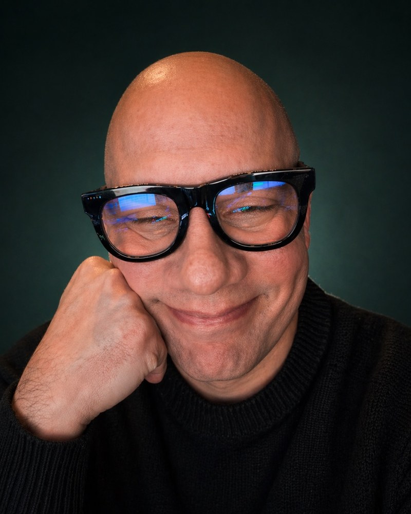 Harold Martinez, smiling, wearing thick black-framed glasses